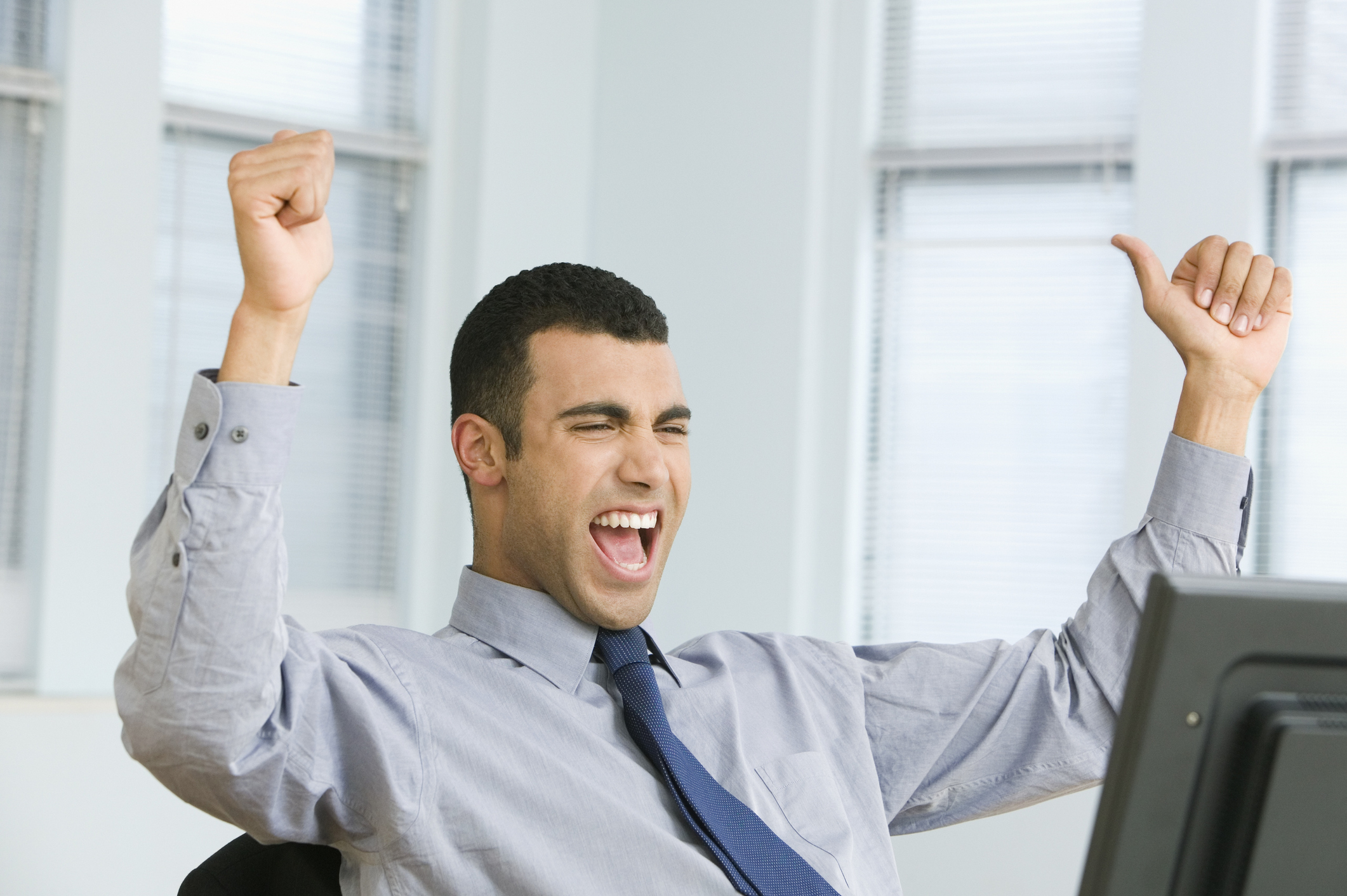 Man at computer raising his arms in celebration