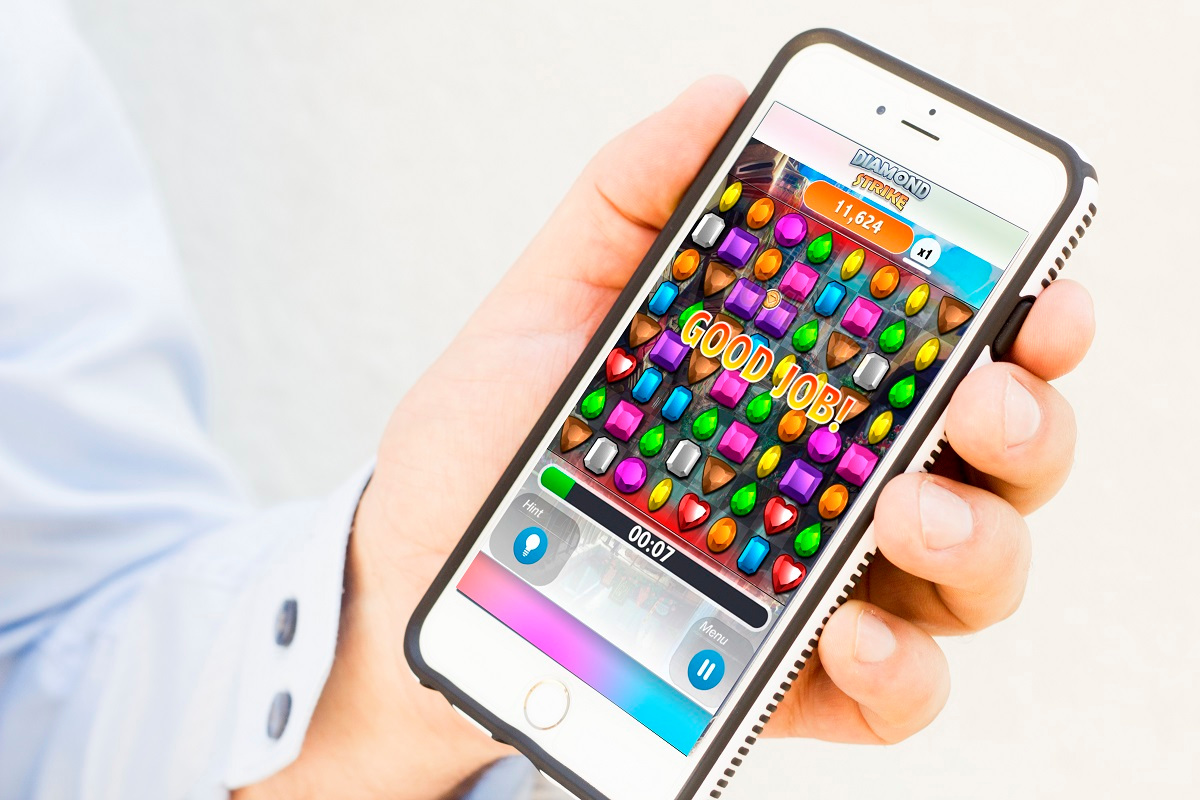A man holding a smartphone with the game Diamond Strike on it
