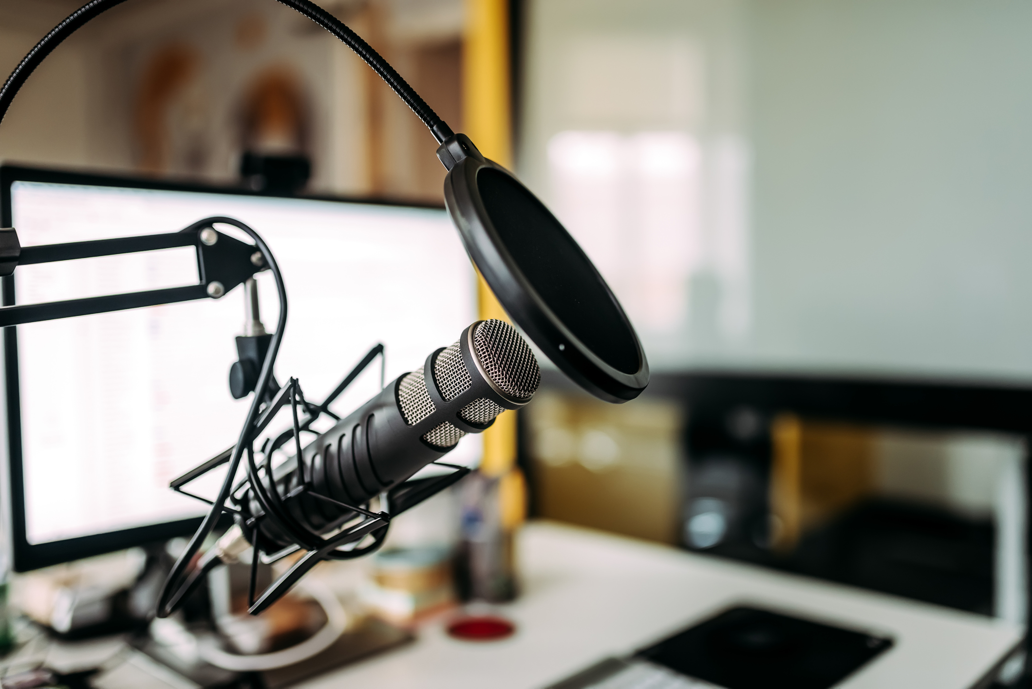 Pop filter over a microphone set up in front of a computer screen.