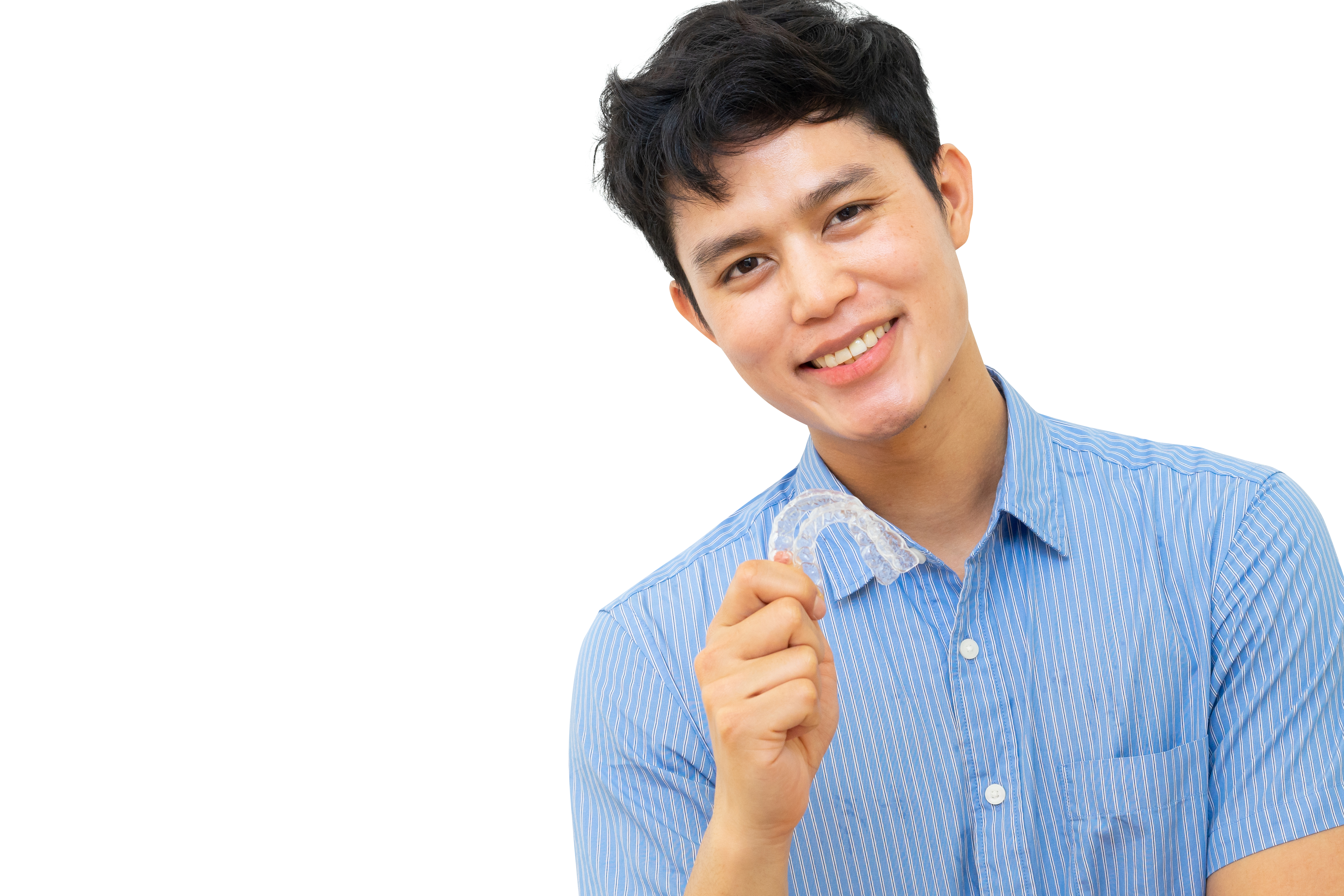 A young man smiles as he holds up a clear dental aligner.