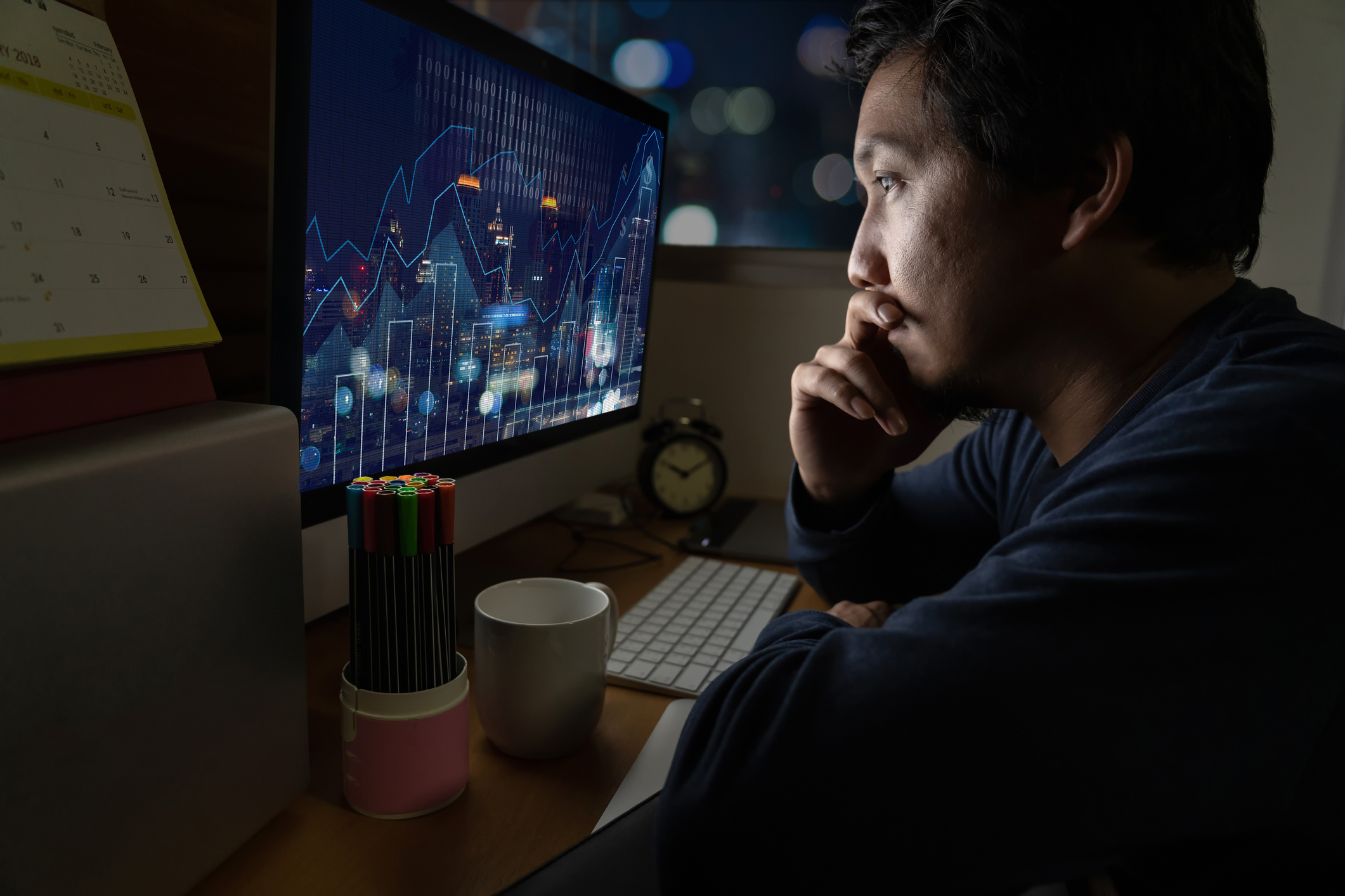 A trader considers a stock chart in a dark room.