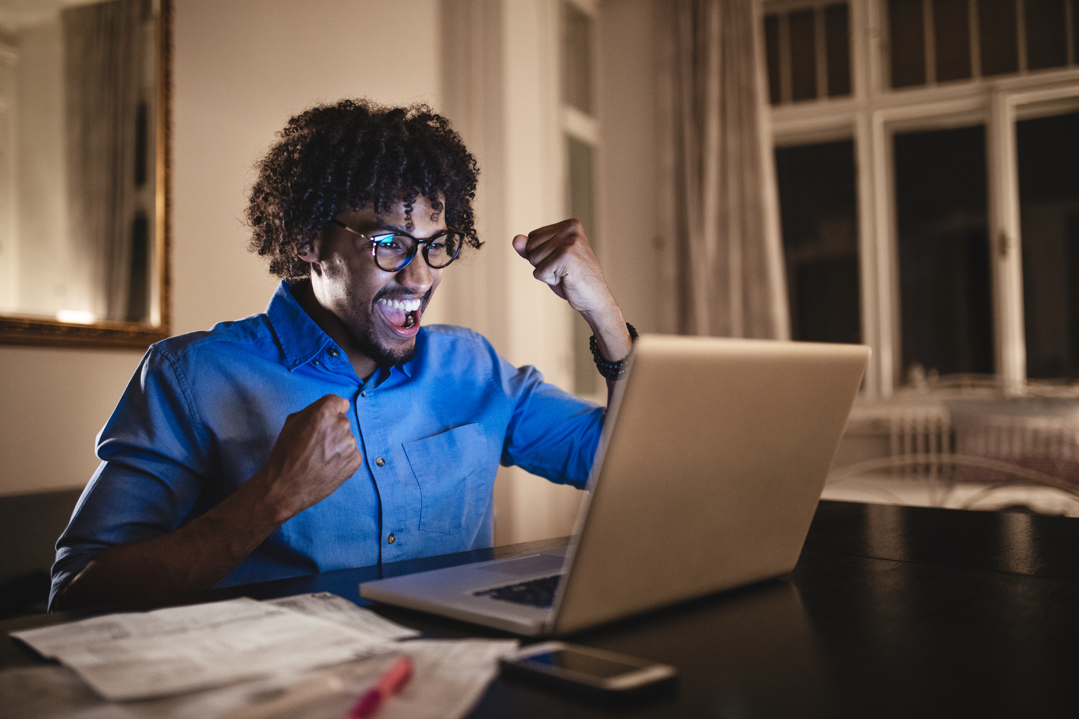 Man at laptop smiling and raising fists