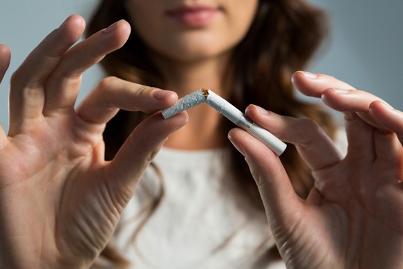 A woman snaps a cigarette in half.