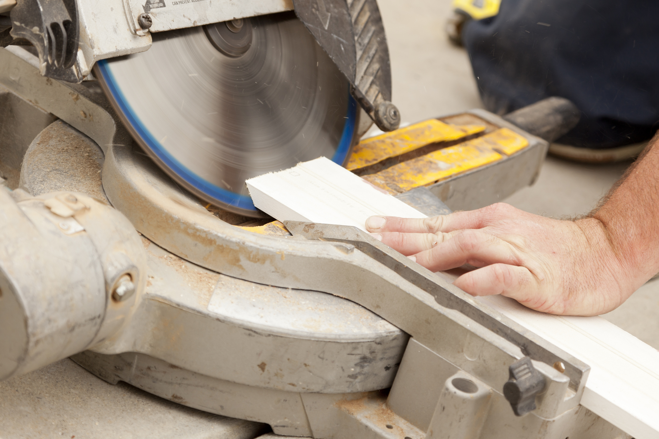 Some hands are using a miter saw.