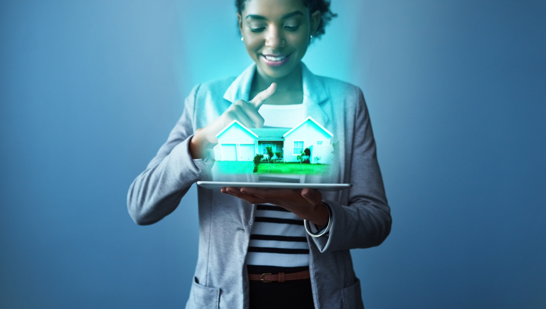 A young woman using a tablet to show a digital projection of a property.