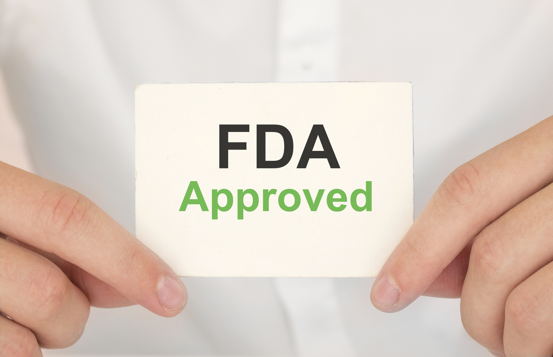 Hands holding a white card with "FDA Approved" printed on it