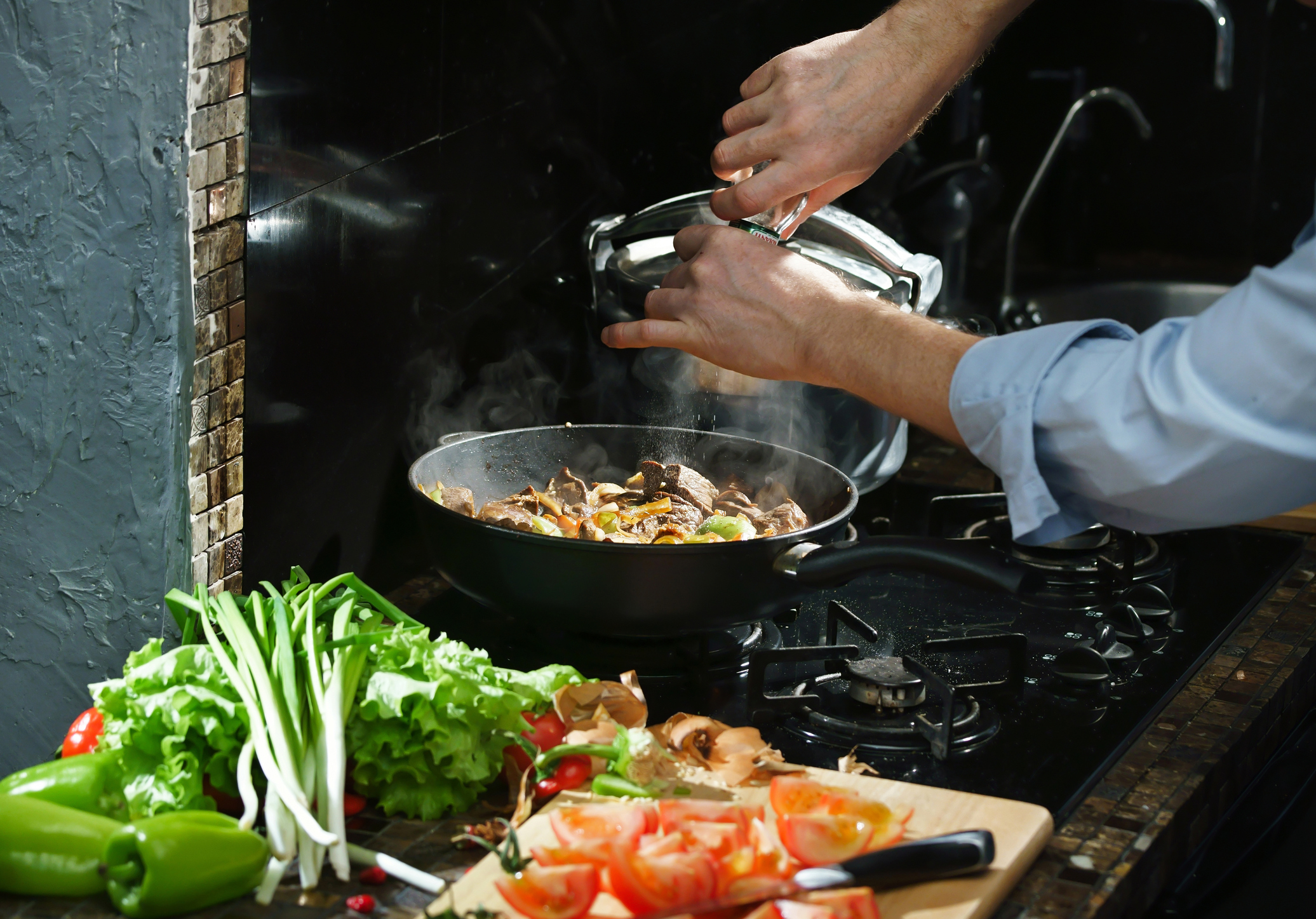 A home chef adds spice to a dish.