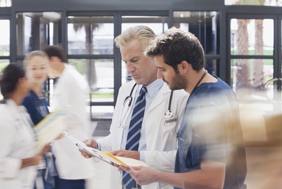 Medical professionals talking in a hospital or clinic lobby.