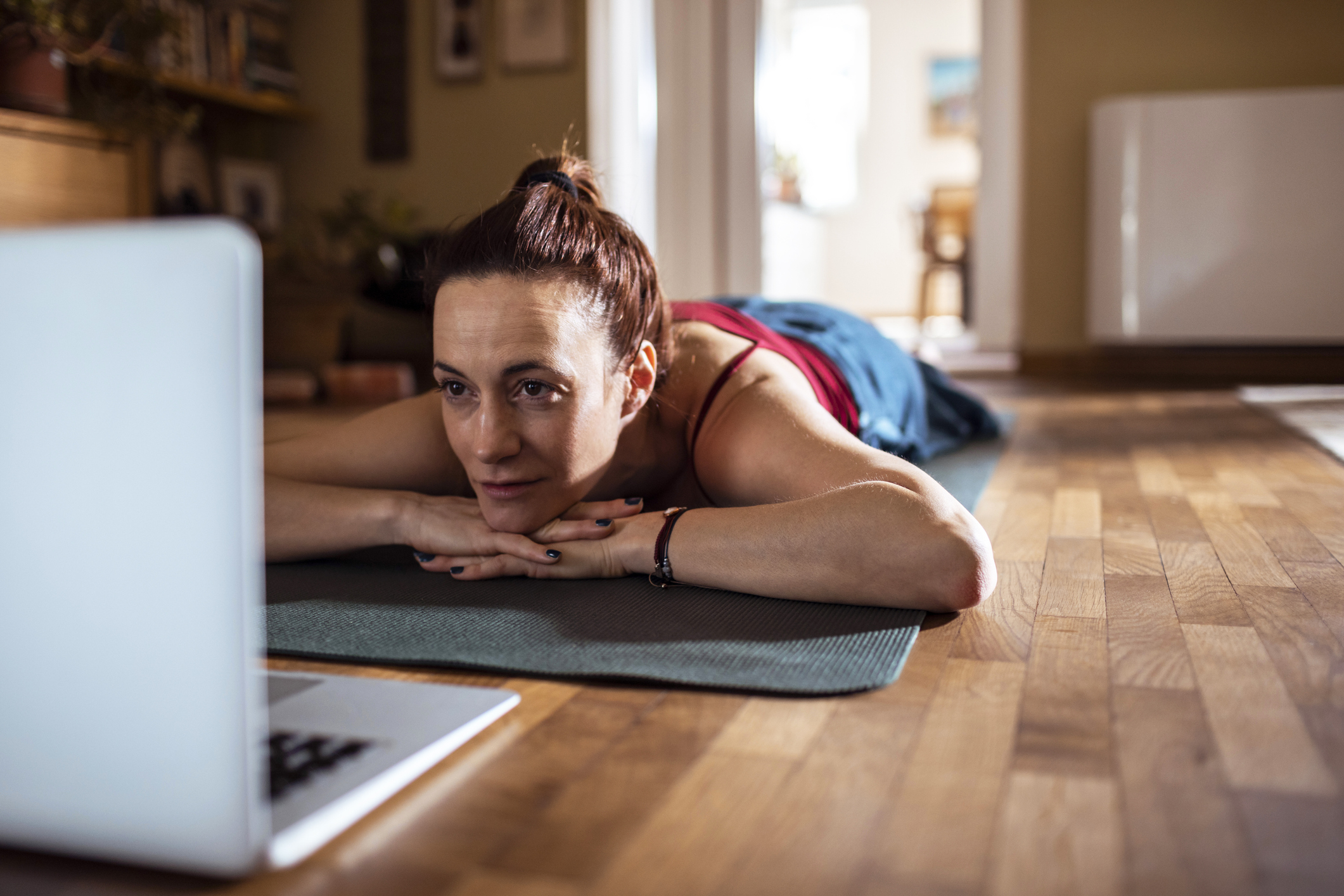 Young woman using a laptop while doing yoga.