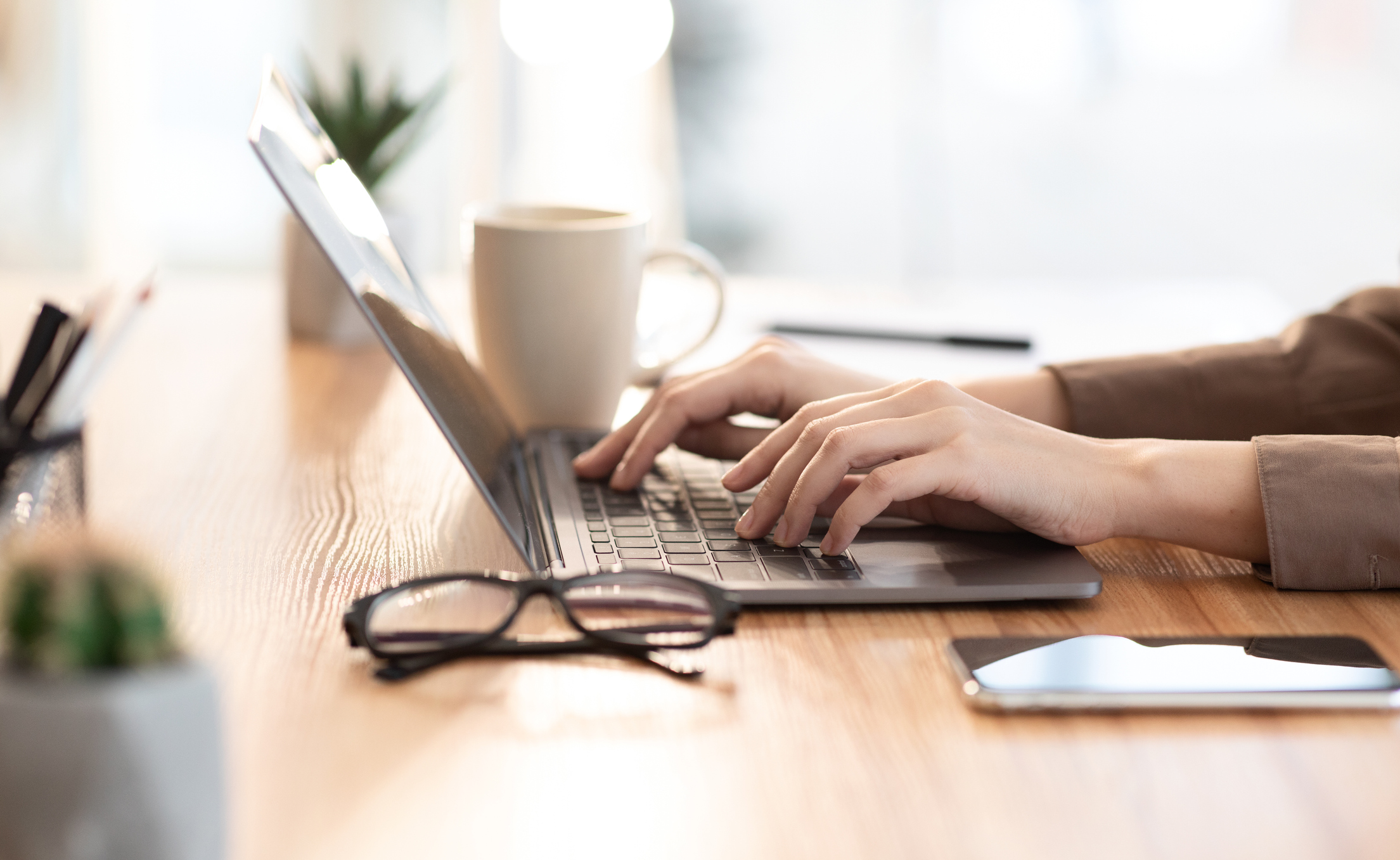 A person using a laptop with a coffee cup nearby.