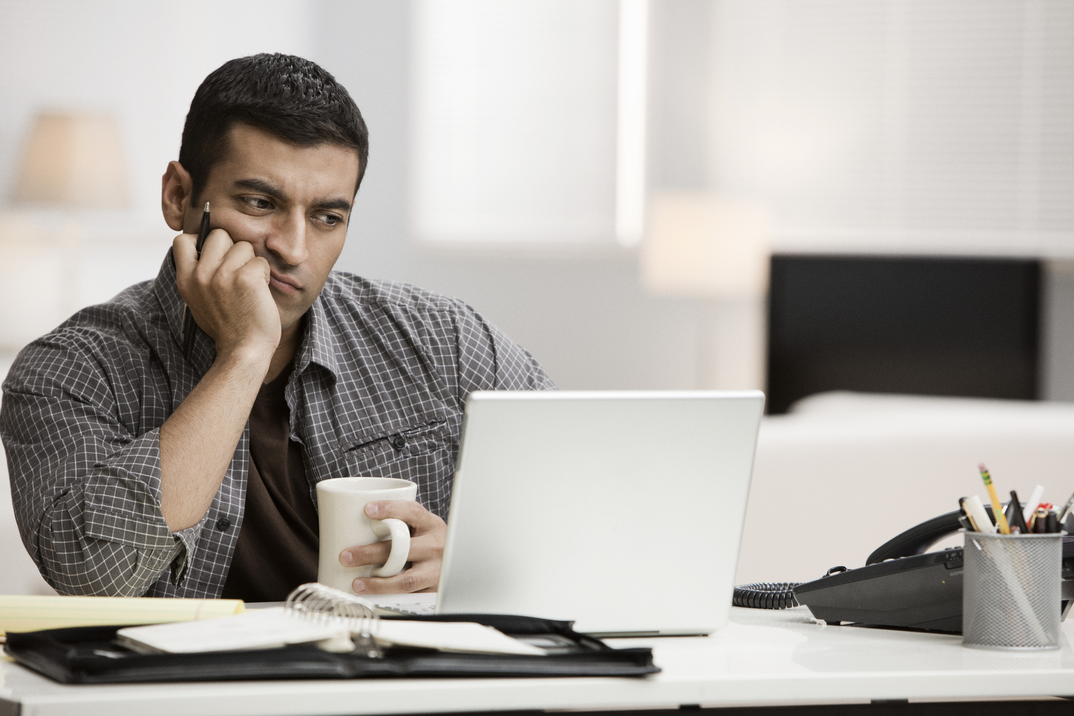 Man staring at laptop with confused expression