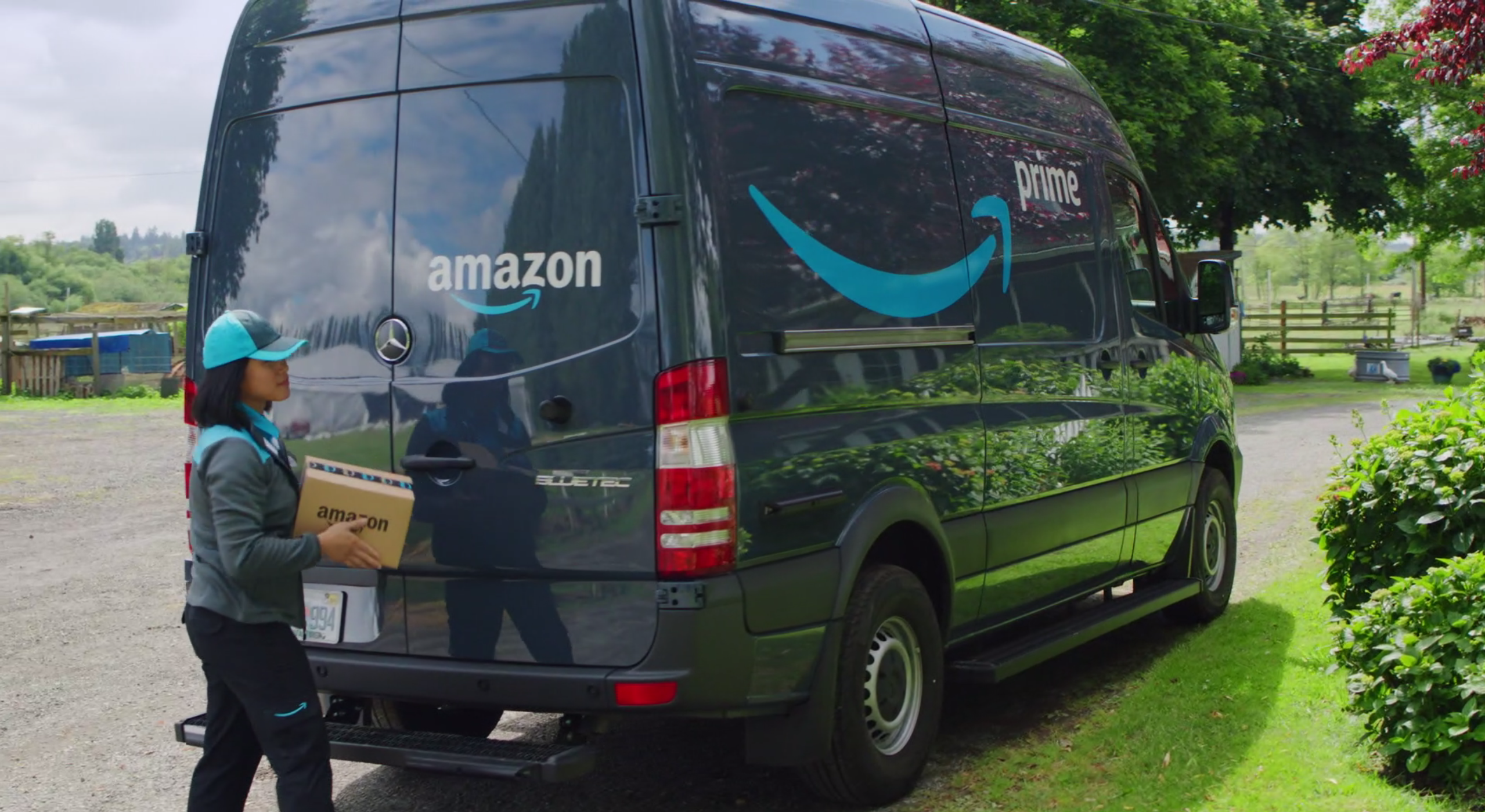 An Amazon delivery worker carries a package next to an Amazon delivery truck