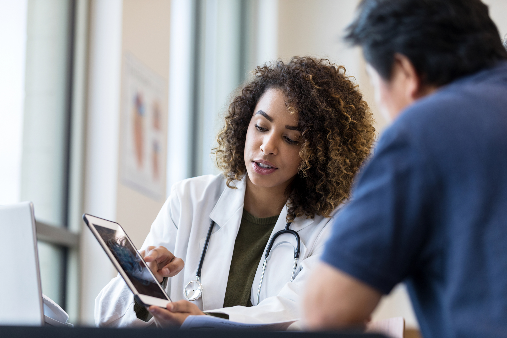 Two medical professionals review data on a tablet.