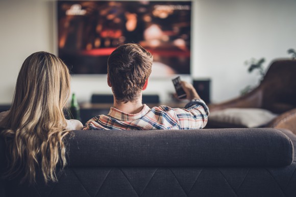 Two people watching TV on a couch. 