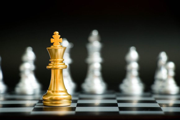 A gold king chess piece amid silver pieces, depicting a winner.