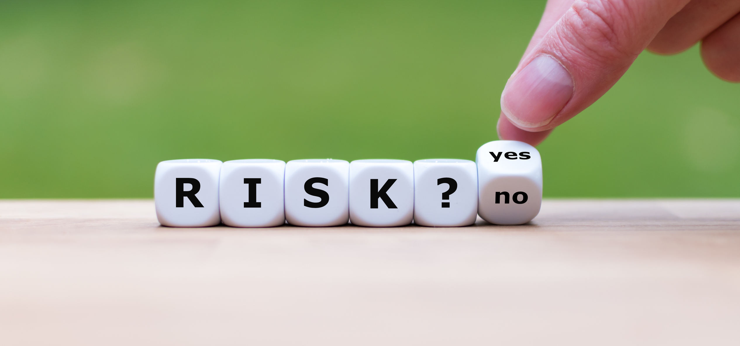 Blocks spelling RISK? with hand turning another block from NO to YES