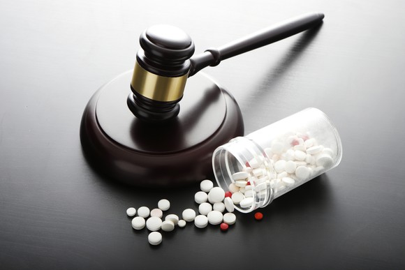 A gavel and spilled pill bottle on a table.