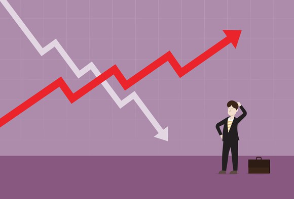 Rising and falling arrowed  charts crossing one another while confused businessman looks on.