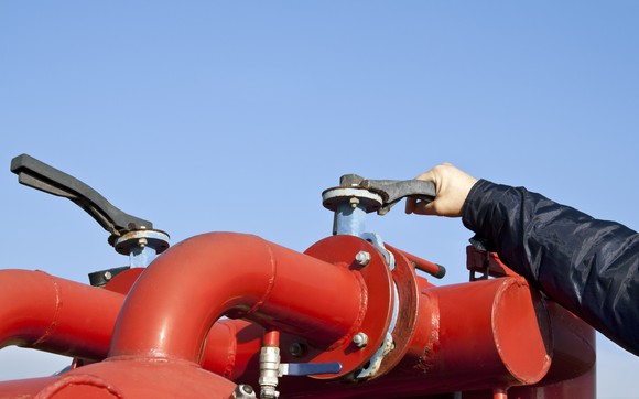 A worker opens the valve on a gas pipe. 