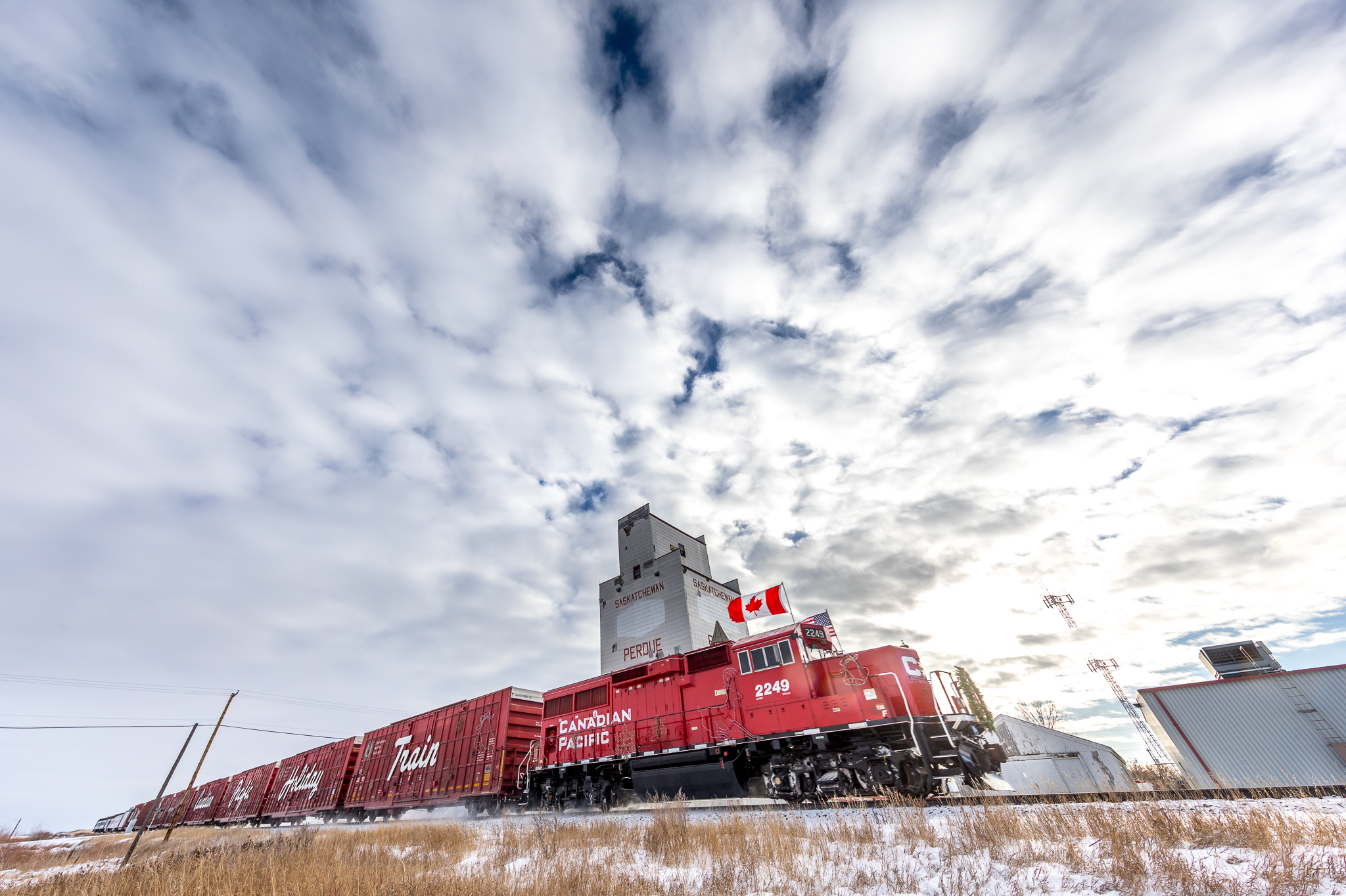 A Canadian Pacific train passes by a grain silo.