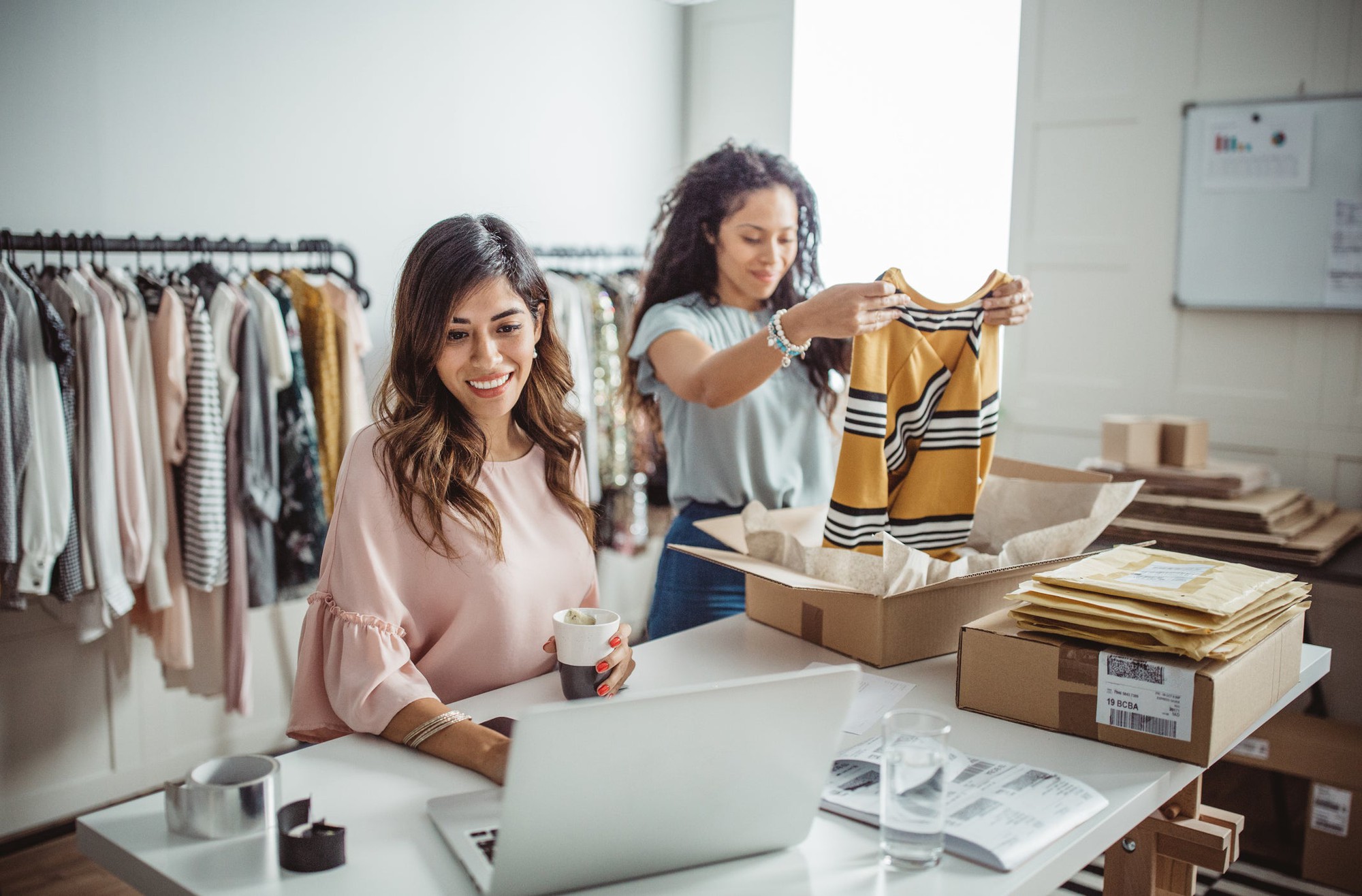 Two business owners fold clothes as they fill online orders.