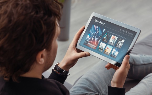 A man browsing videos on a tablet.