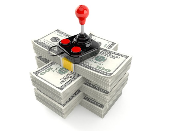A gaming joystick on top of a pile of cash.