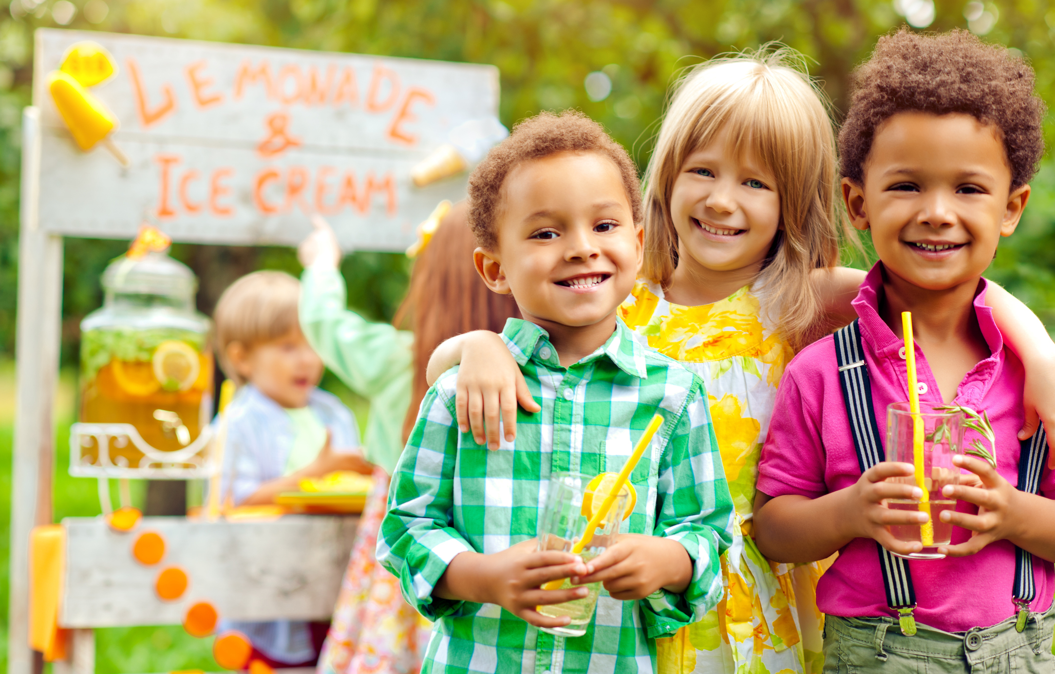 A group of kids drinking lemonade at a lemonade and ice cream stand.