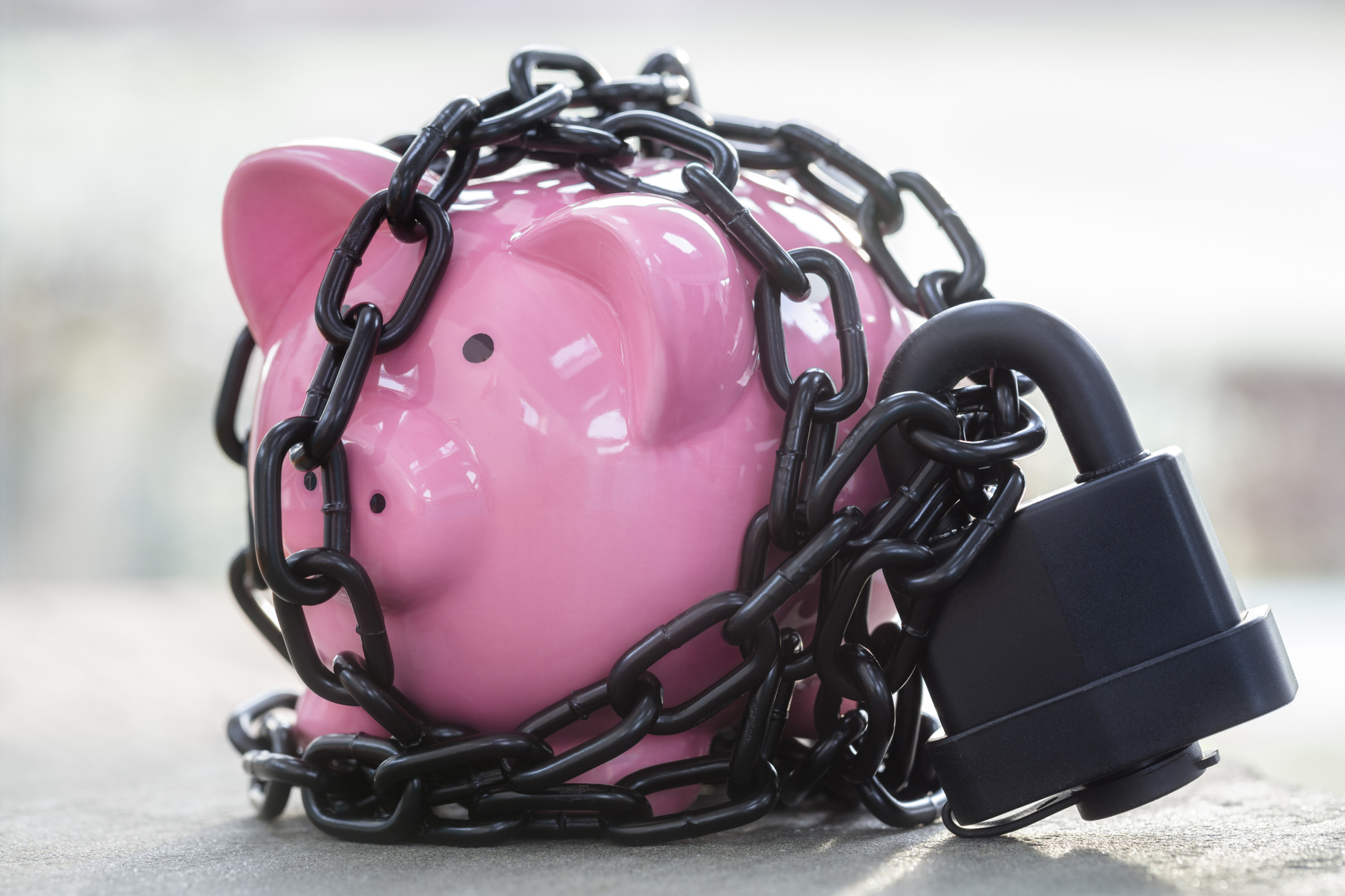 A piggy bank locked away by a padlock and chain.
