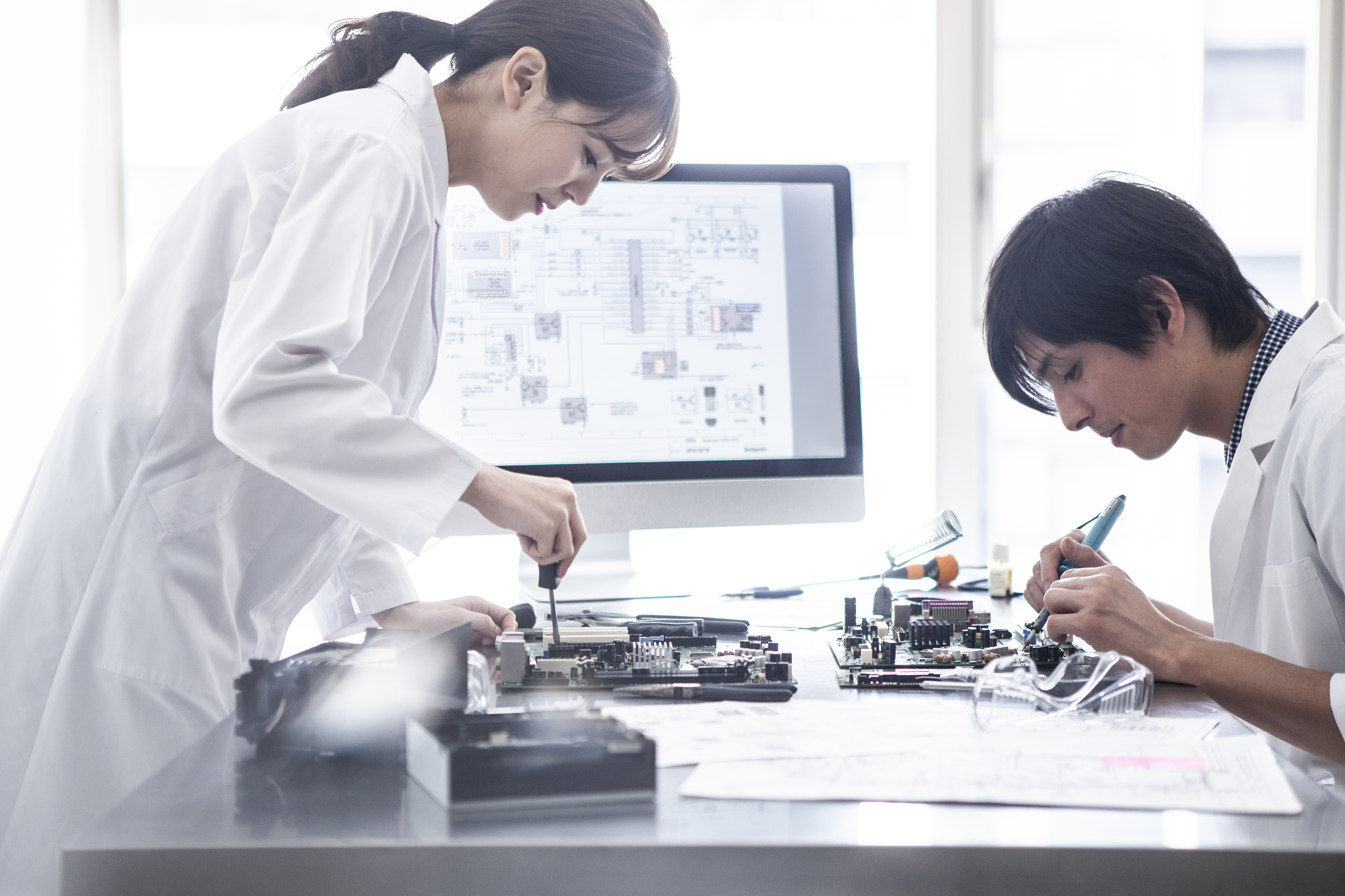 Two people designing a semiconductor system in front of a computer displaying a chip design.