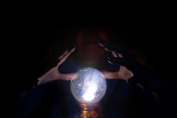 A wizard using a crystal ball in the dark.