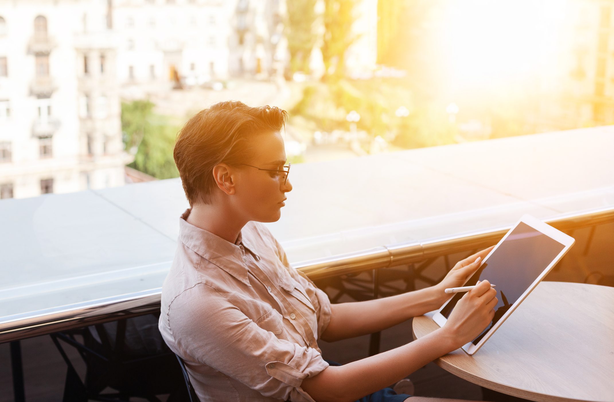 A young woman uses a stylus on her tablet. 