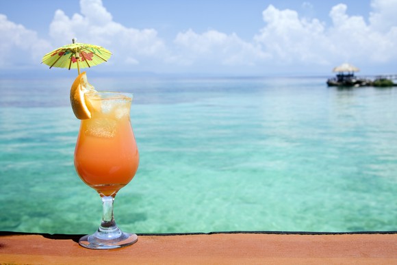 A tropical drink with an umbrella and a view of the ocean. 