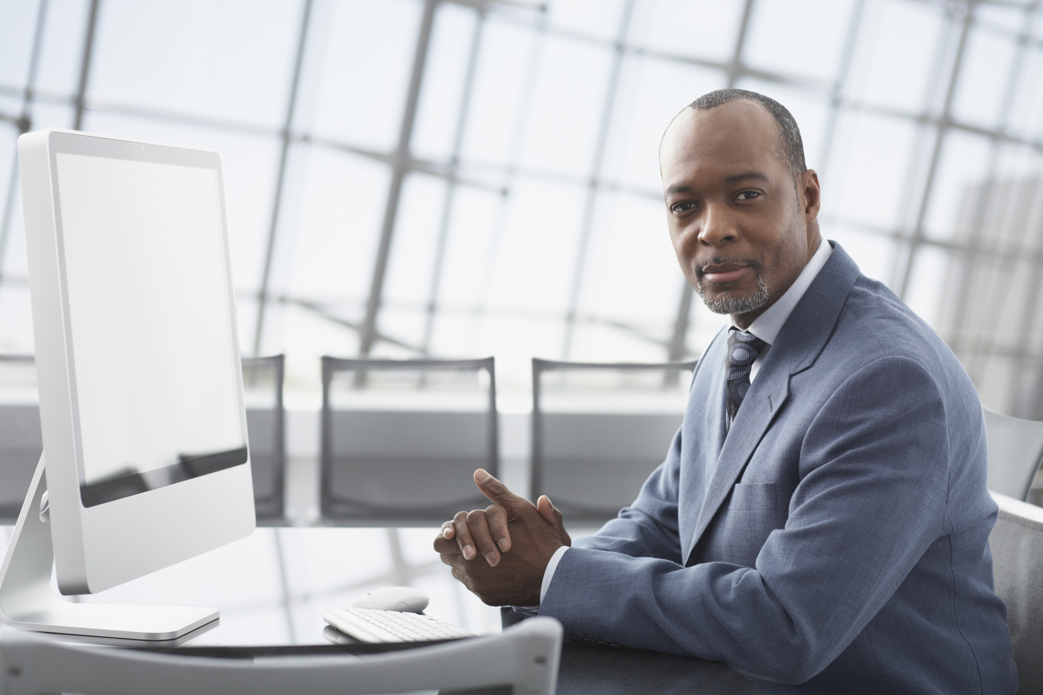 Person in suit with serious expression at table with computer