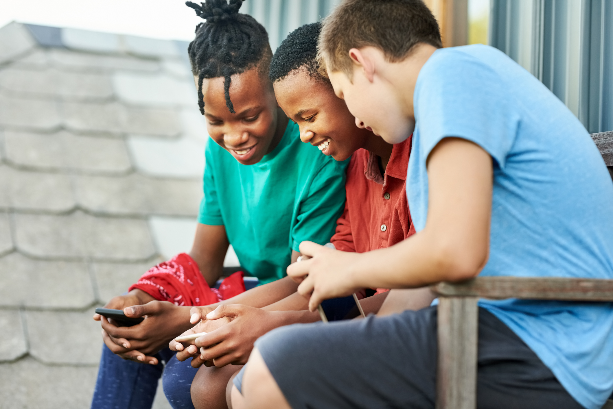 Three young kids having a good time playing a mobile game.
