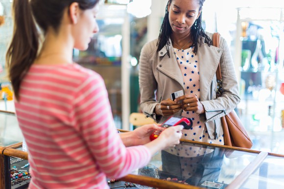 Woman paying for merchandise at a store with a payment card.