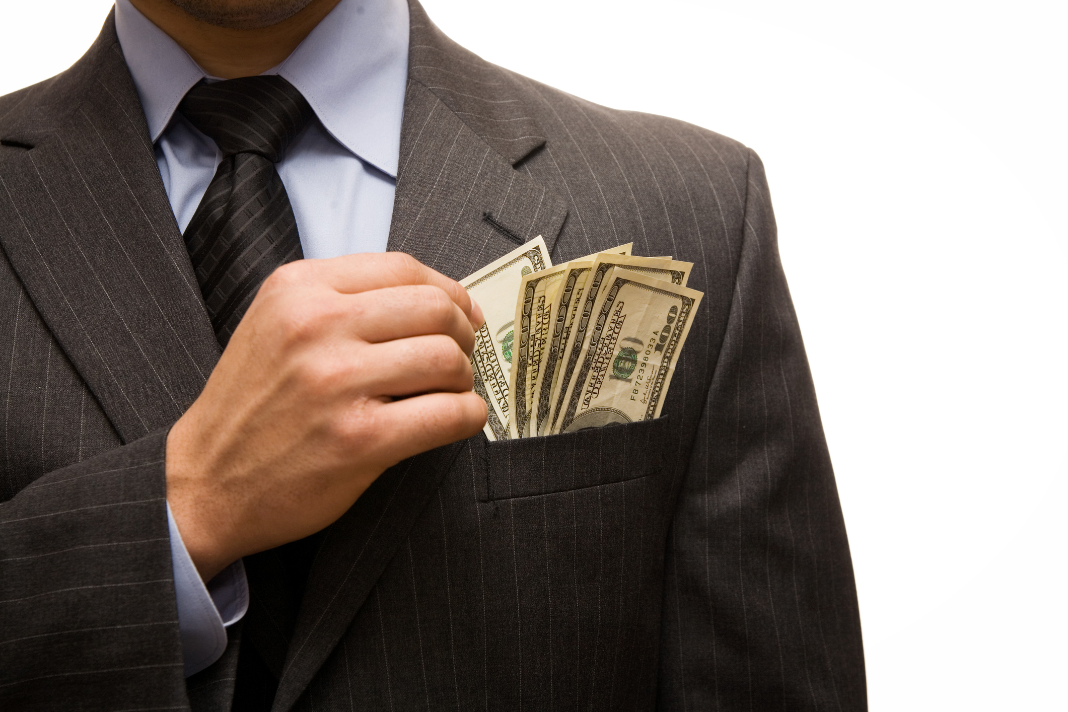 A businessman stuffs his pocket with $100 bills.