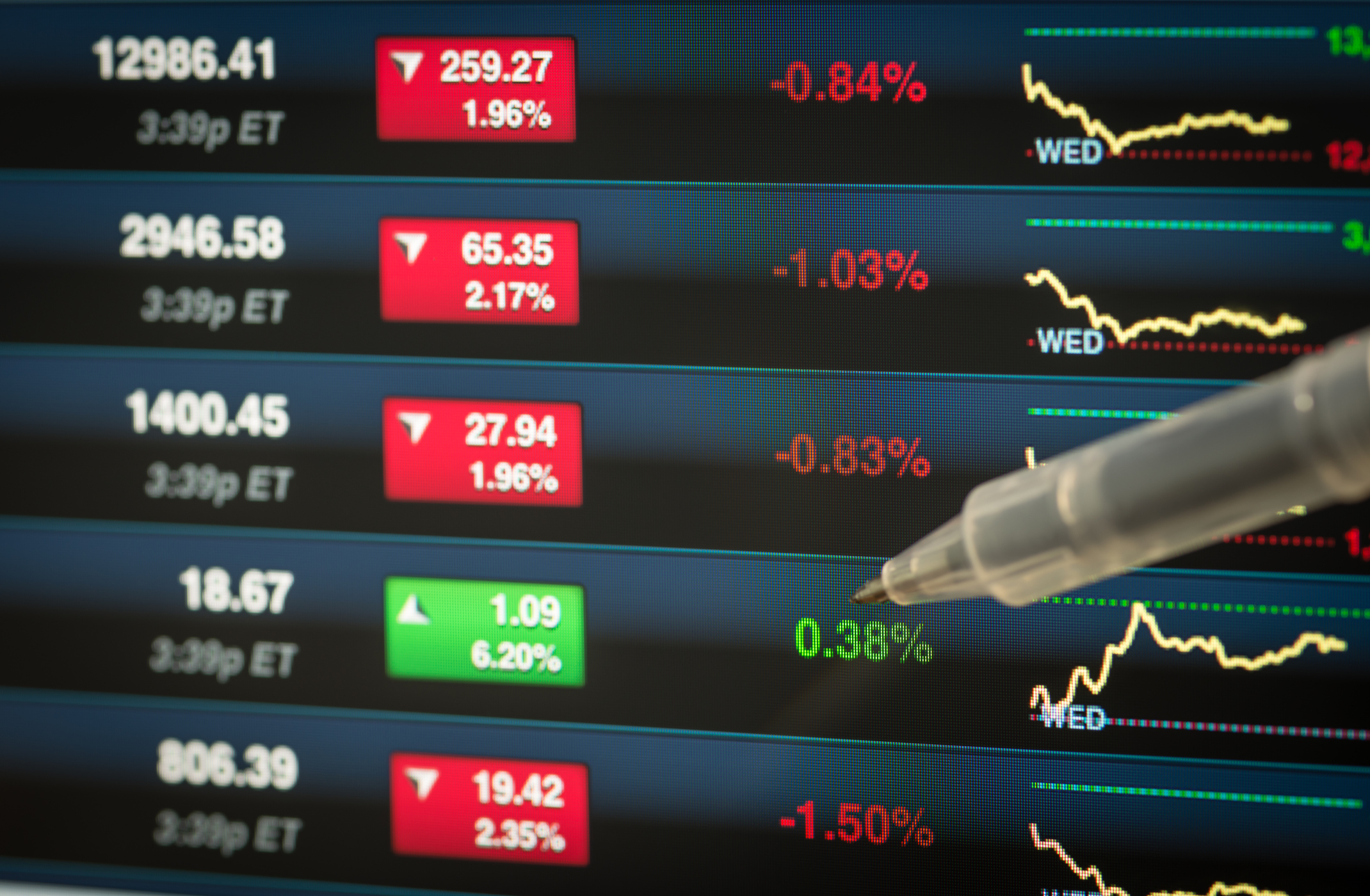 A pen pointing to a stock going up among several decliners.