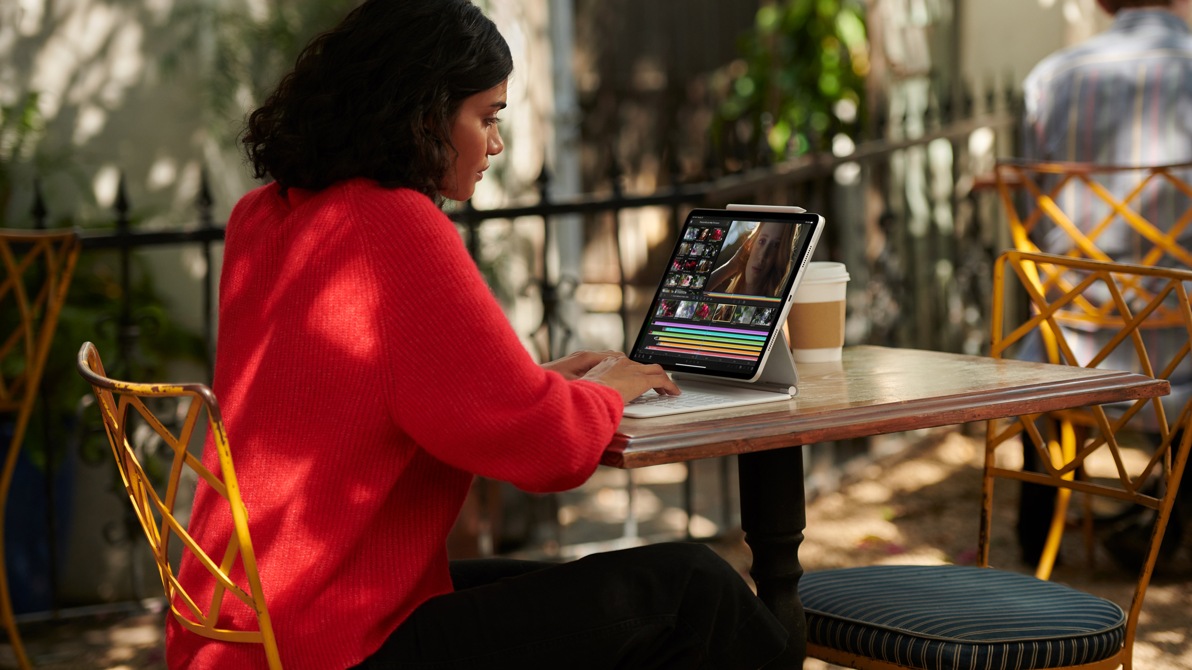 Person using tablet while sitting at a table outside.