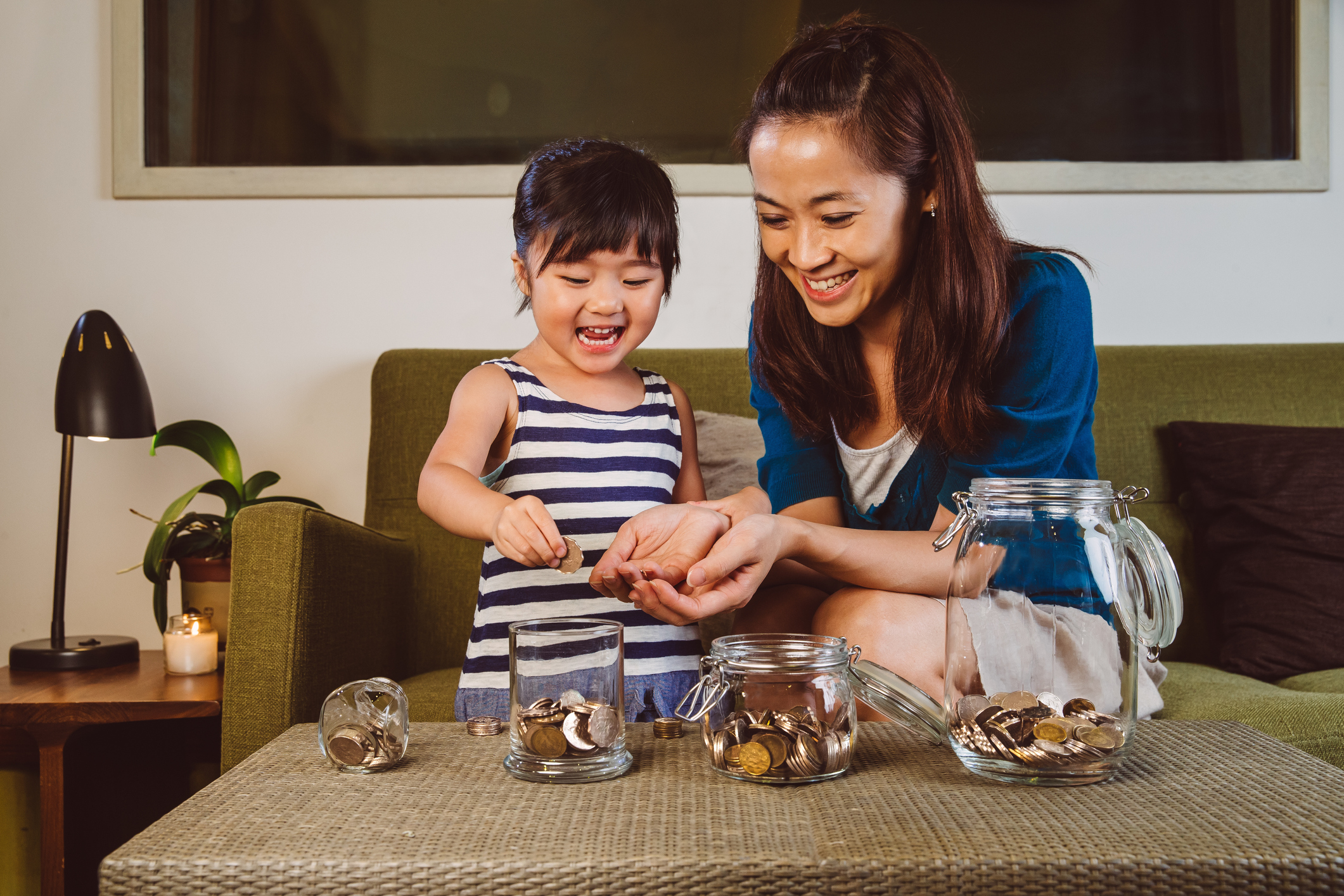 parent and child placing coins in savings jars