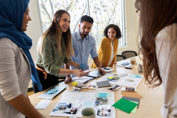 A group of young professionals in an office discussing ad design ideas.