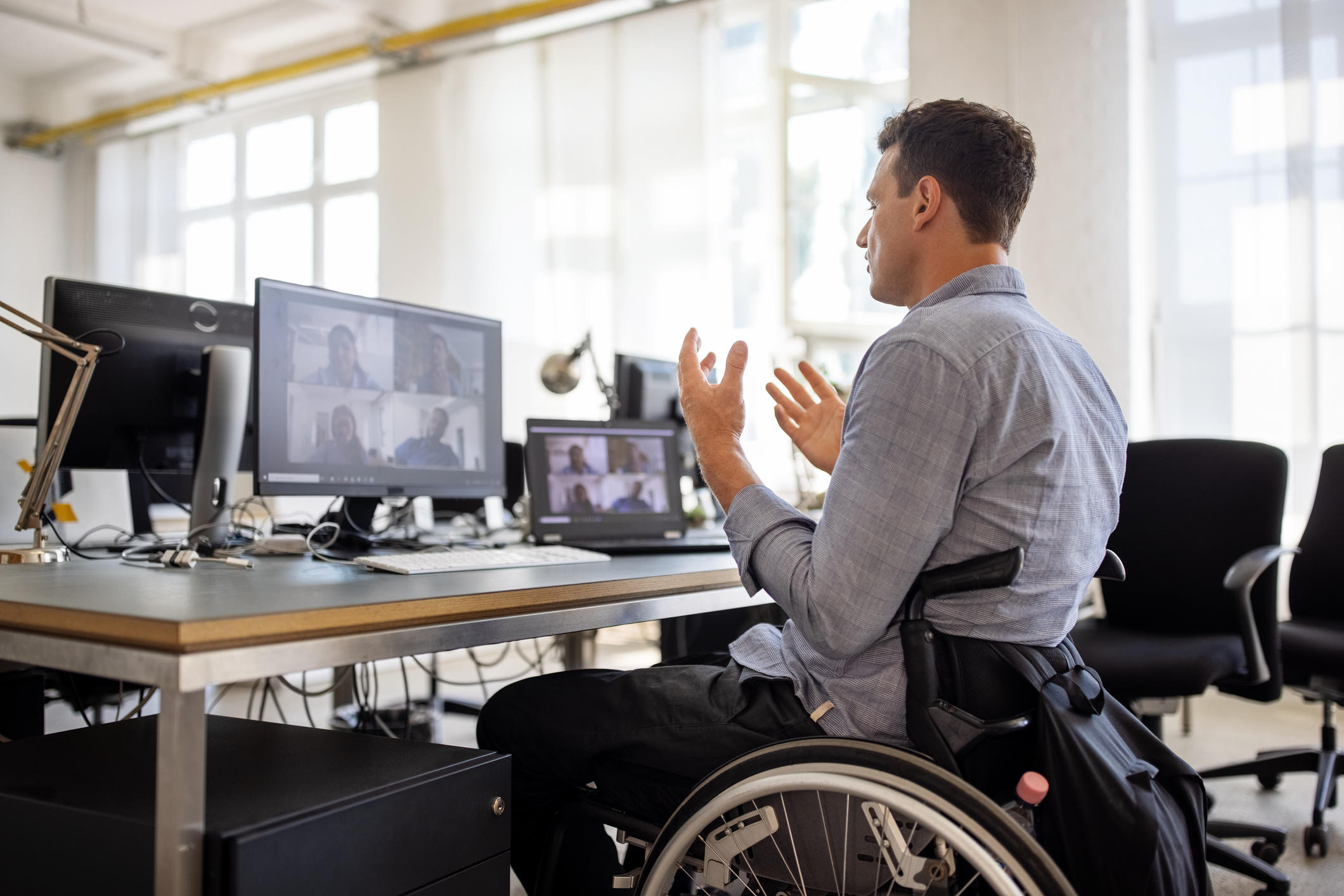 A person sitting at a desk, using video conferencing software to speak with others.