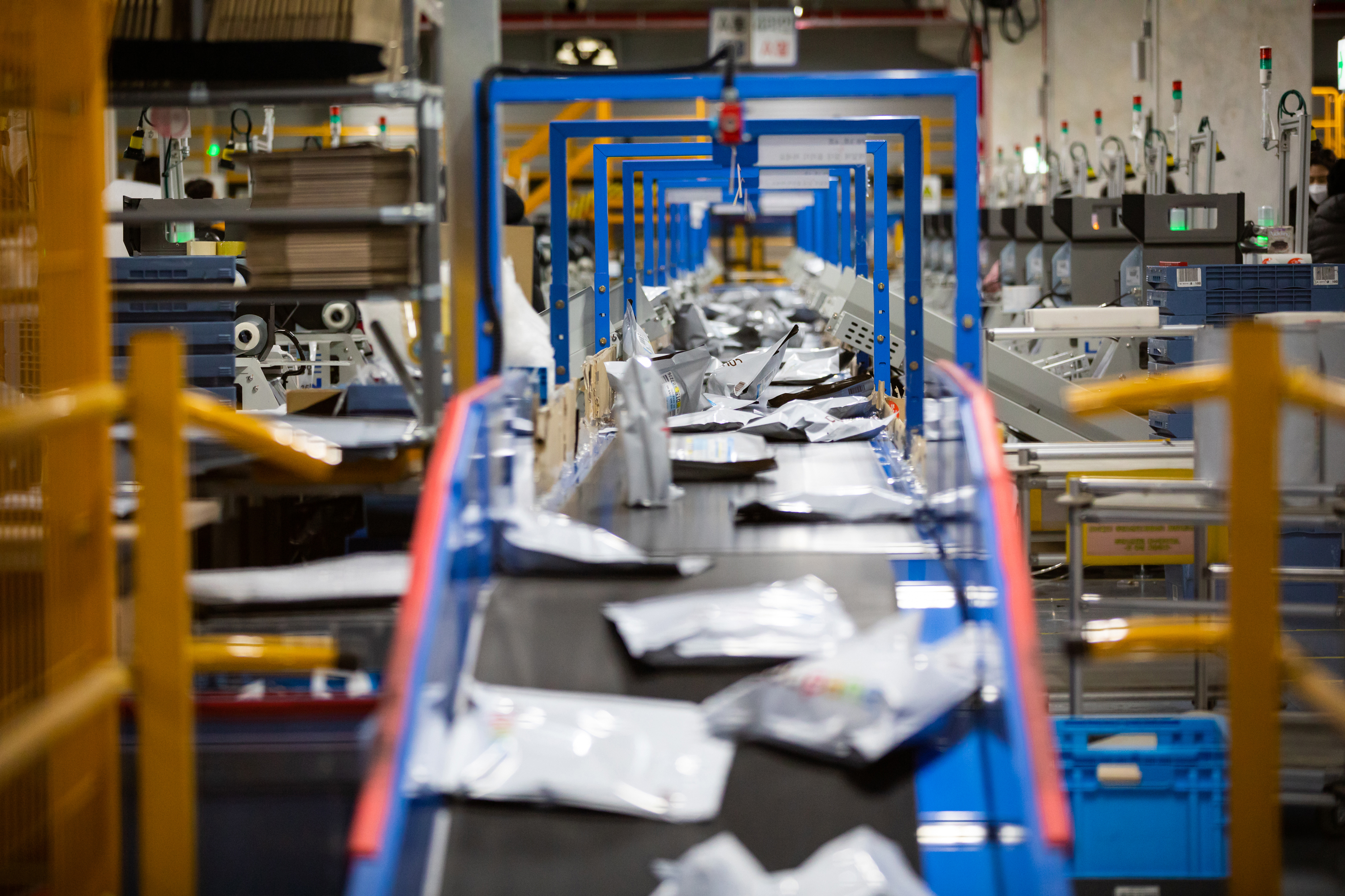 Plastic packages moving along a conveyor belt in Coupang's fulfillment center.