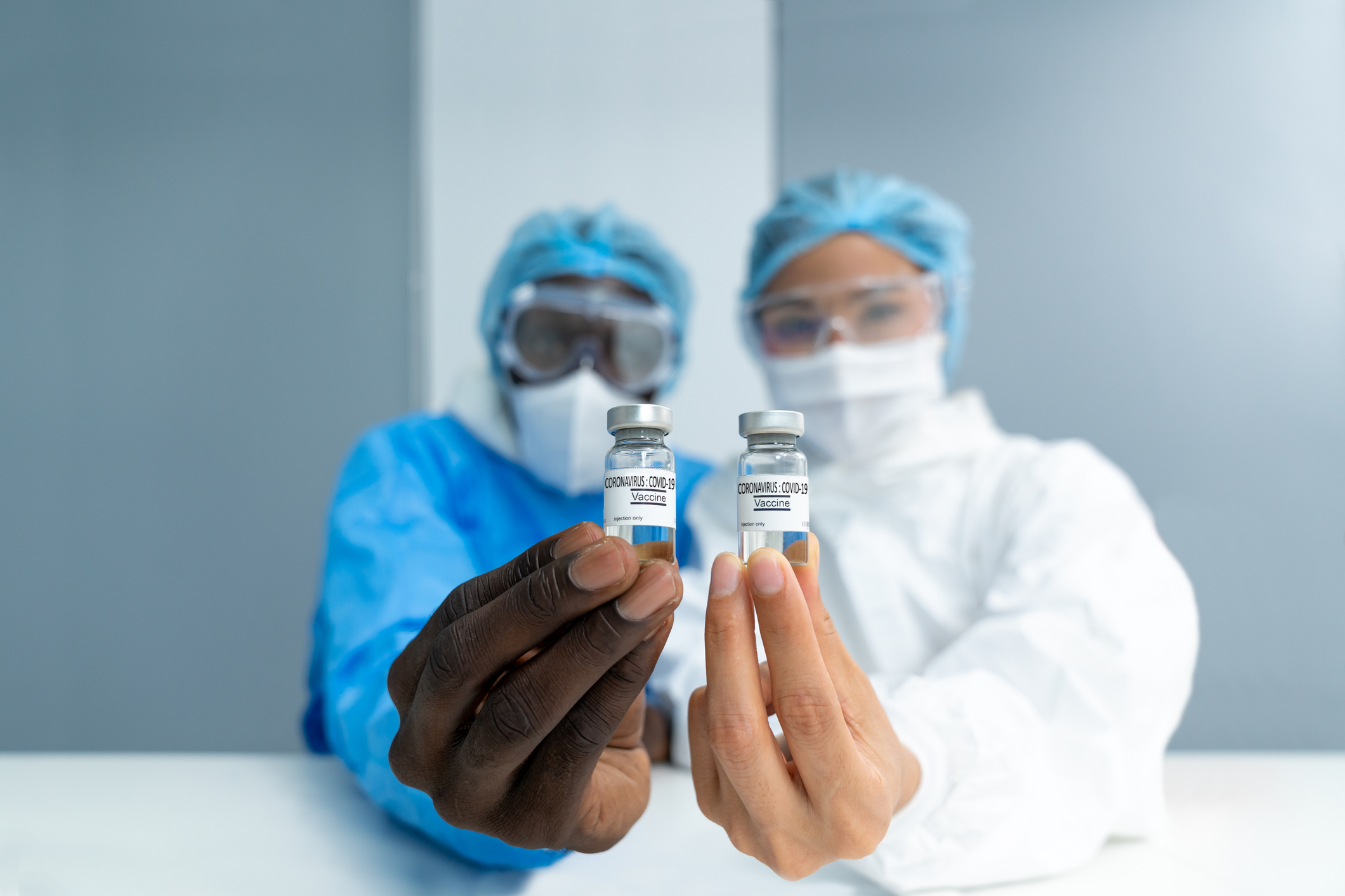 Two researchers hold out vials of coronavirus vaccine.