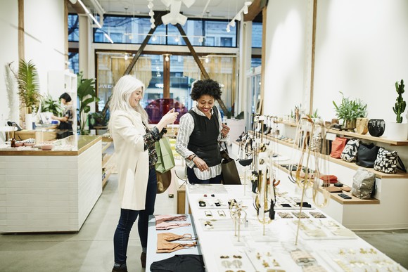 Two people shopping in a store with offwhite walls and high ceilings.