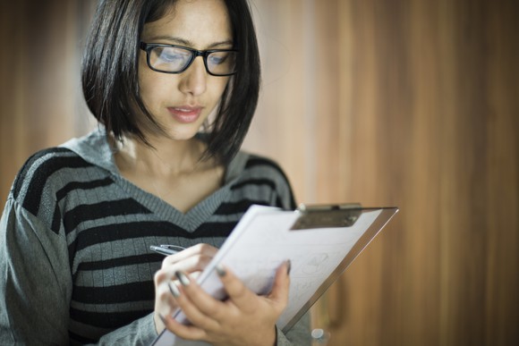 A woman takes notes on a clipboard.