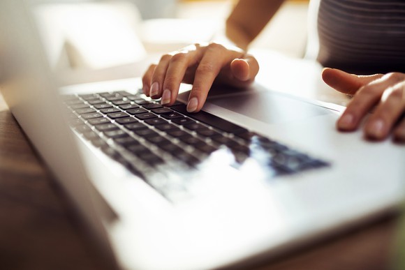 Hands on a laptop keyboard.