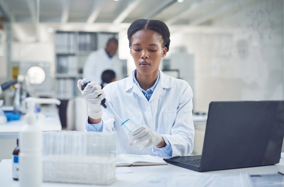 A researcher works in a lab in front of a laptop.