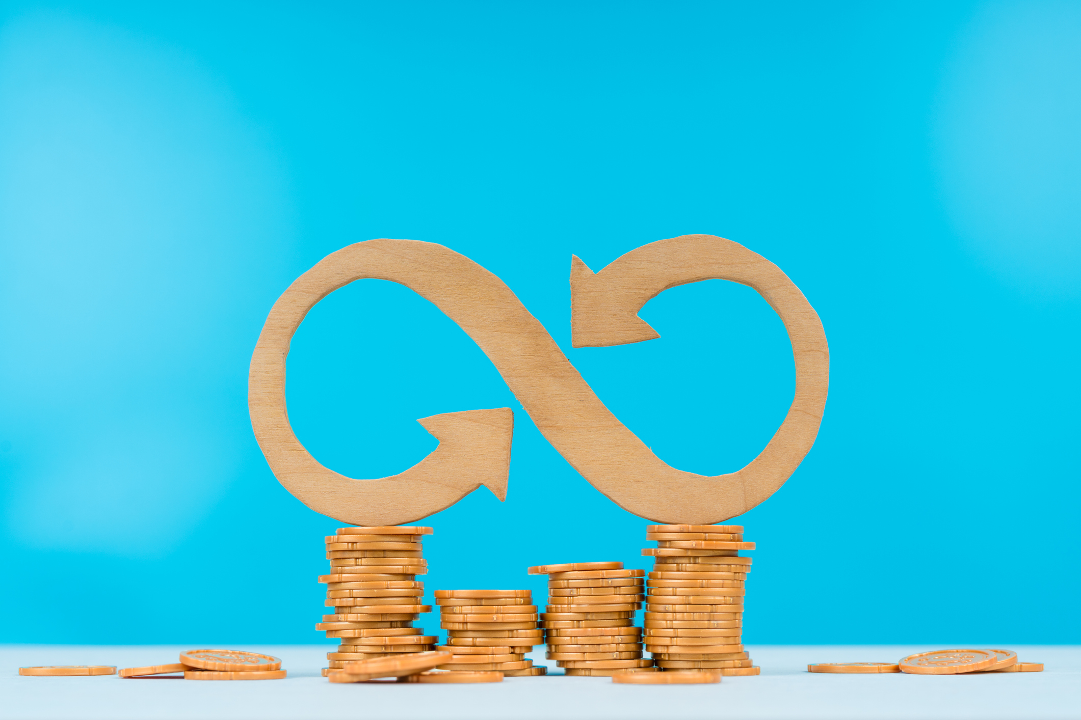 Wooden infinity sign on top of wooden coins.