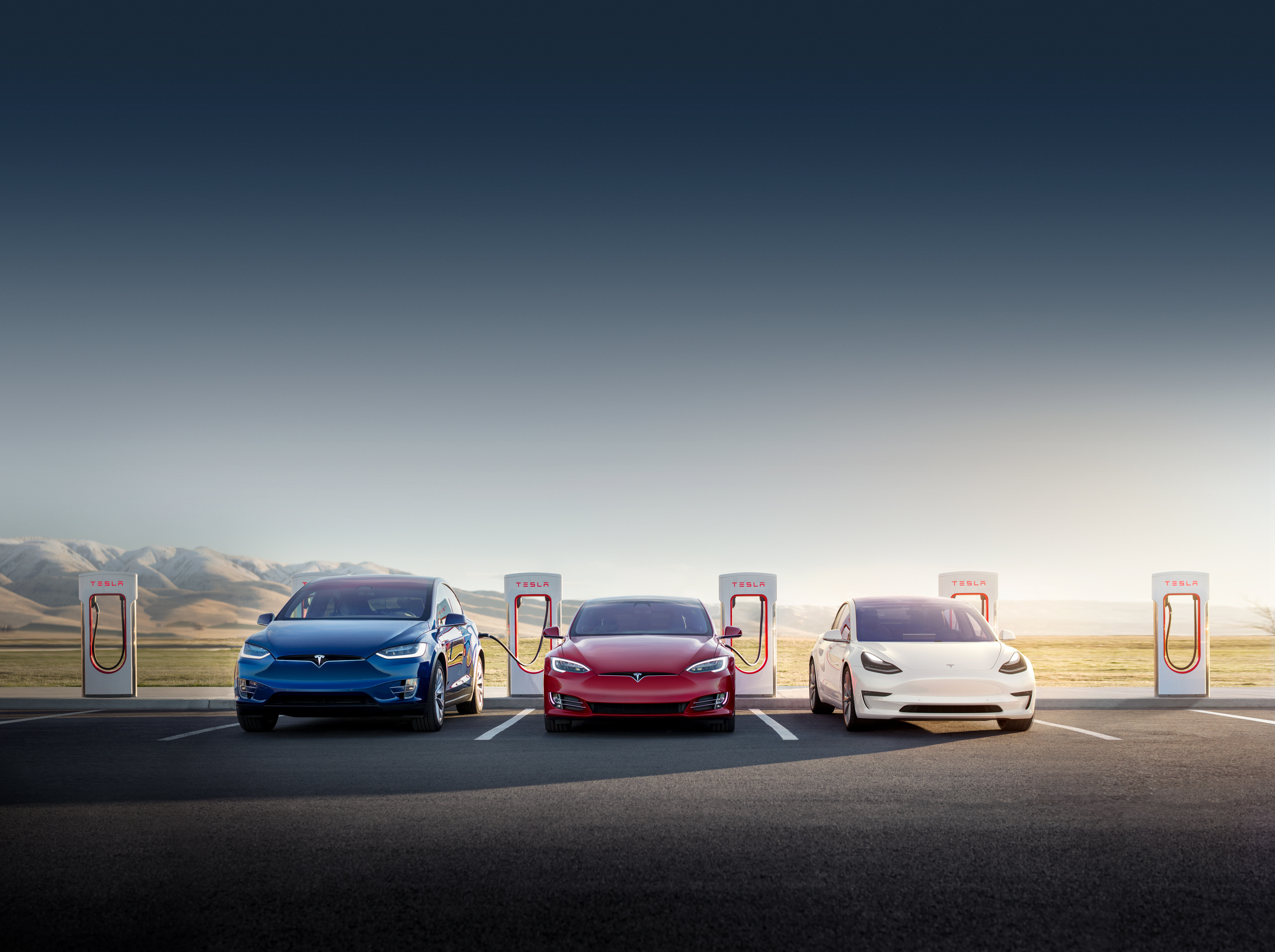Three Tesla vehicles charging at a Supercharger location